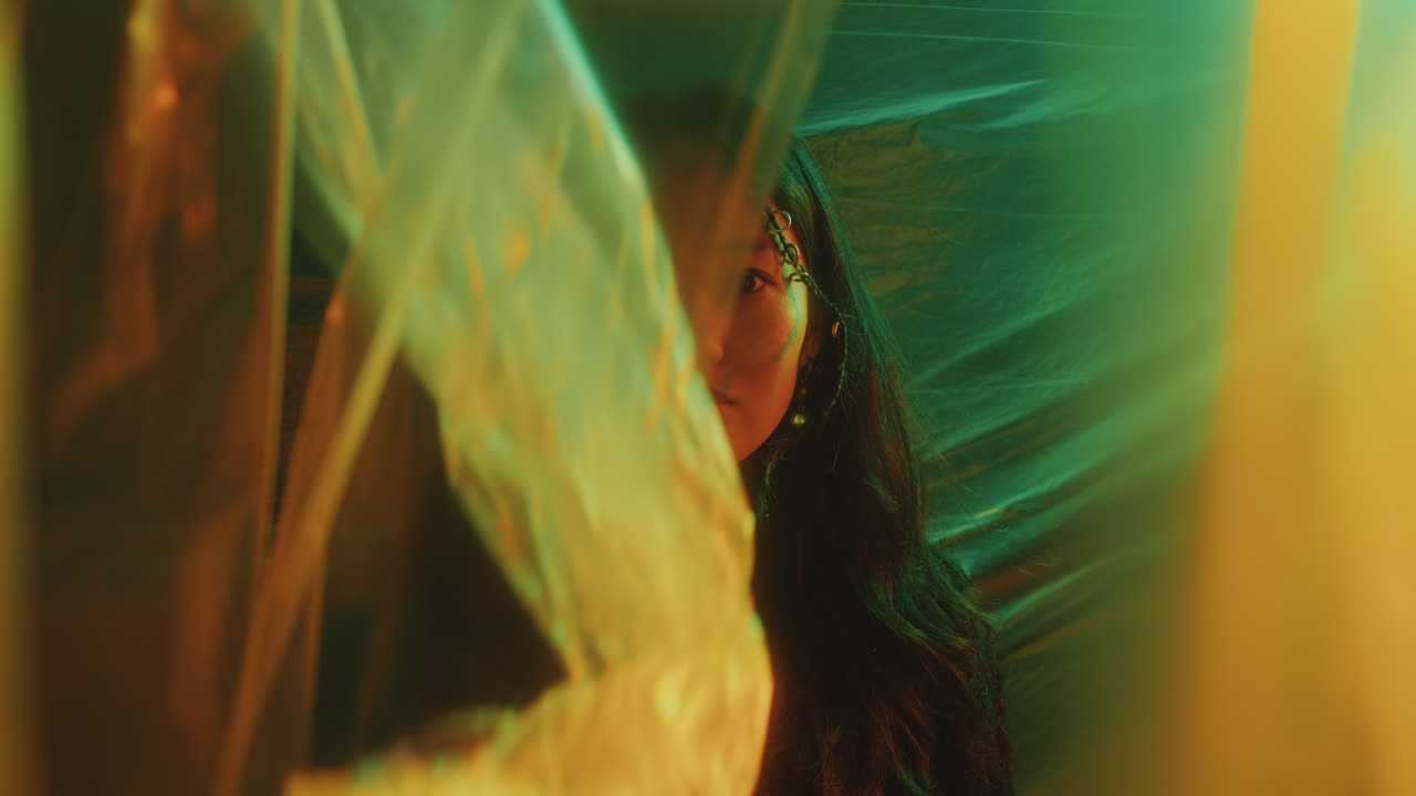 Portrait of Beautiful Asian Woman behind Cellophane Curtains in Neon Light