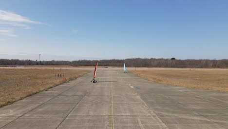 dos yates de vela terrestre girando en la esquina y dirigiéndose hacia la cámara en la estación aérea naval de south weymouth - base naval desmantelada