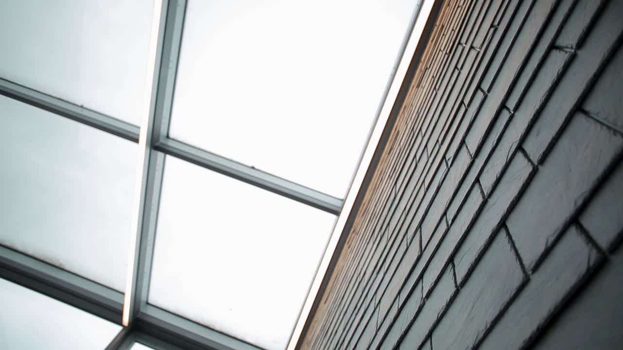 Glass ceiling and brick wall from a low angle, creating an abstract urban look