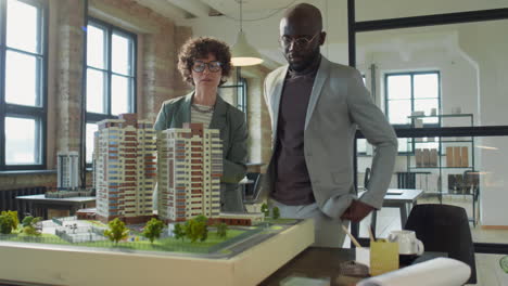 architects discussing a large building model in an office setting