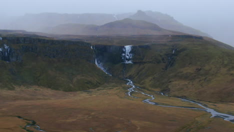 Vergrößerte-Luftaufnahme-Von-Bewölktem-Himmel,-Bergen,-Kargem-Boden,-Tälern,-Wasserfällen-Und-Bächen-Im-Isländischen-Berg-Kirkjufell-In-Der-Nähe-Von-Grundarfjordour