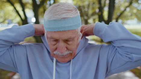 Portrait-of-athletic-senior-sport-runner-man-training,-listening-music-in-earphones,-wearing-hood