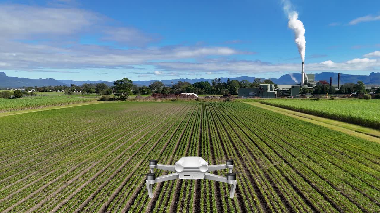Aerial drone animation over farmland towards a distant factory, showcasing vibrant fields and industrial contrast under clear skies