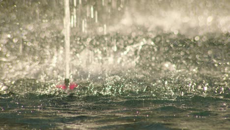 Closeup-view-of-fountain-base-and-water-falling-on-pond-liquid-surface