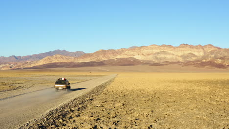 follow through aerial view of single suv jeep on road amidst hot dry barren terrain of death valley national park