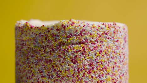 close up studio shot of revolving birthday cake covered with hundreds and thousands decorations 8