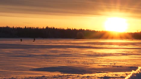 slider shot of people ice fishing, on the frozen sea, in the kvarken archipelago, at sunset, on a sunny, winter evening, in ostrobothnia, finland