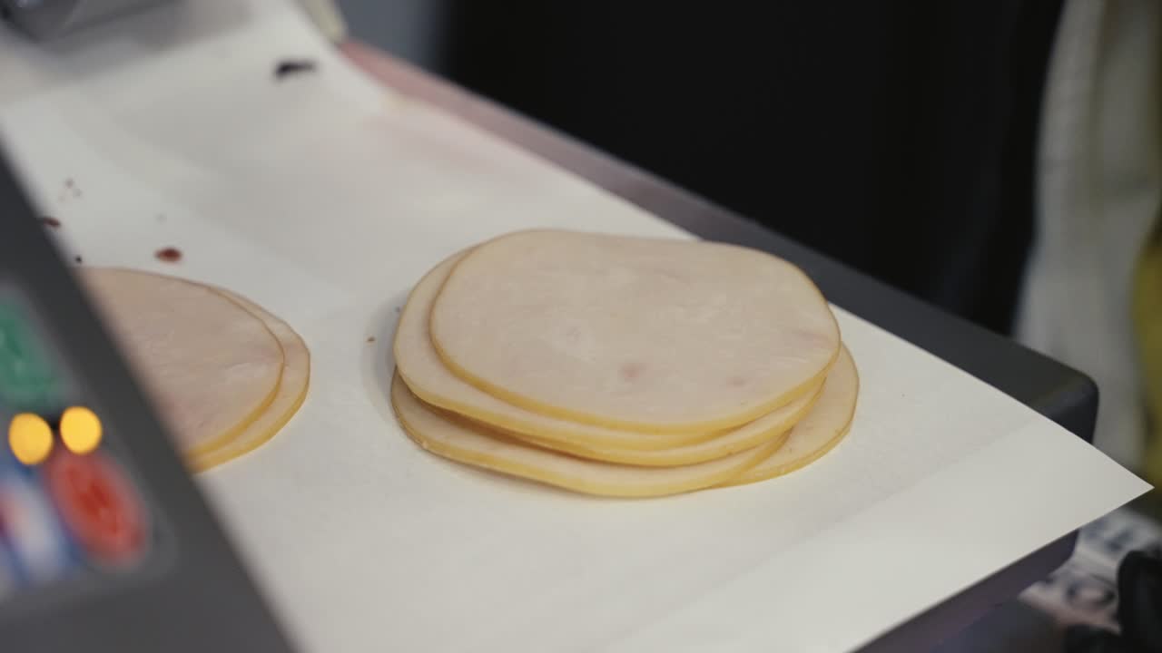 Primo piano di affettatura e pesatura di salumi al banco del supermercato.
