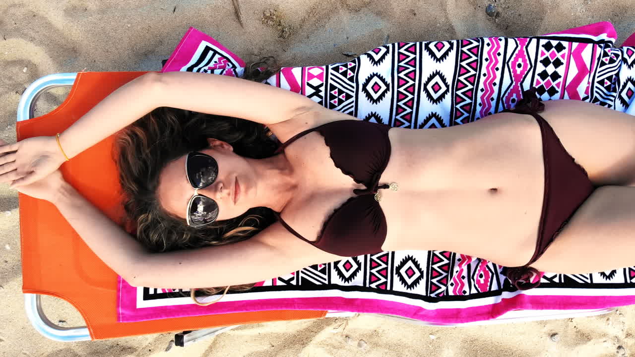 Top view of a woman laying on sunbed, relaxing and looking up