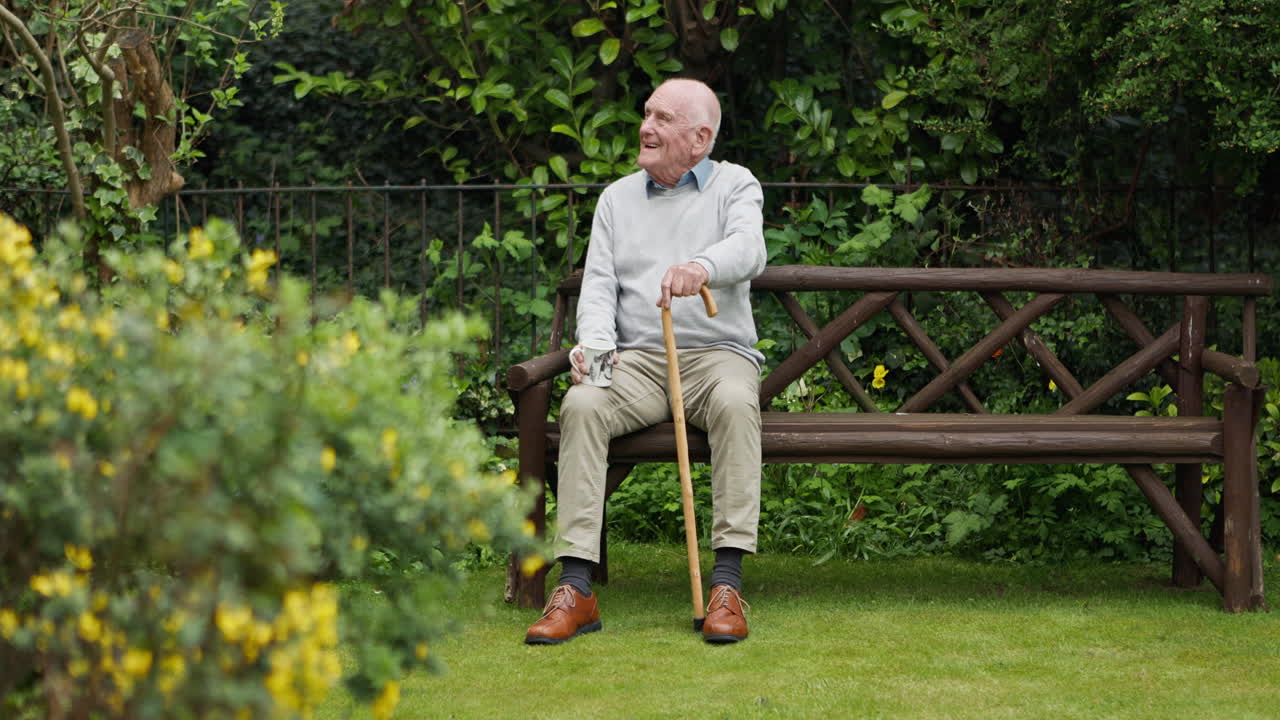 An elderly man sitting on a bench in a garden