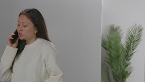 anxious or stressed woman taking call on mobile phone at work in office building