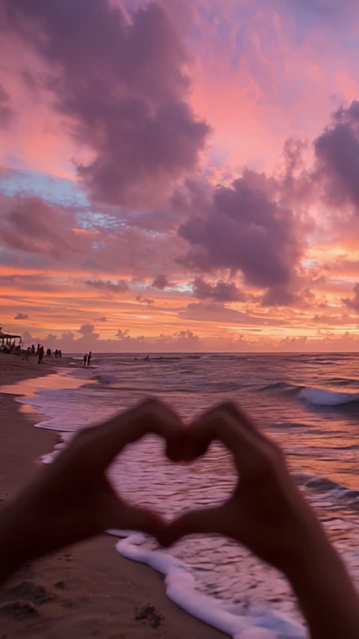 Una Spiaggia Serena al Tramonto: Colori del Cielo Accattivanti e Gesto Simbolico del Cuore Incoronato da Onde Delicate e Sabbia Soffice, Creando un'Atmosfera Romantica