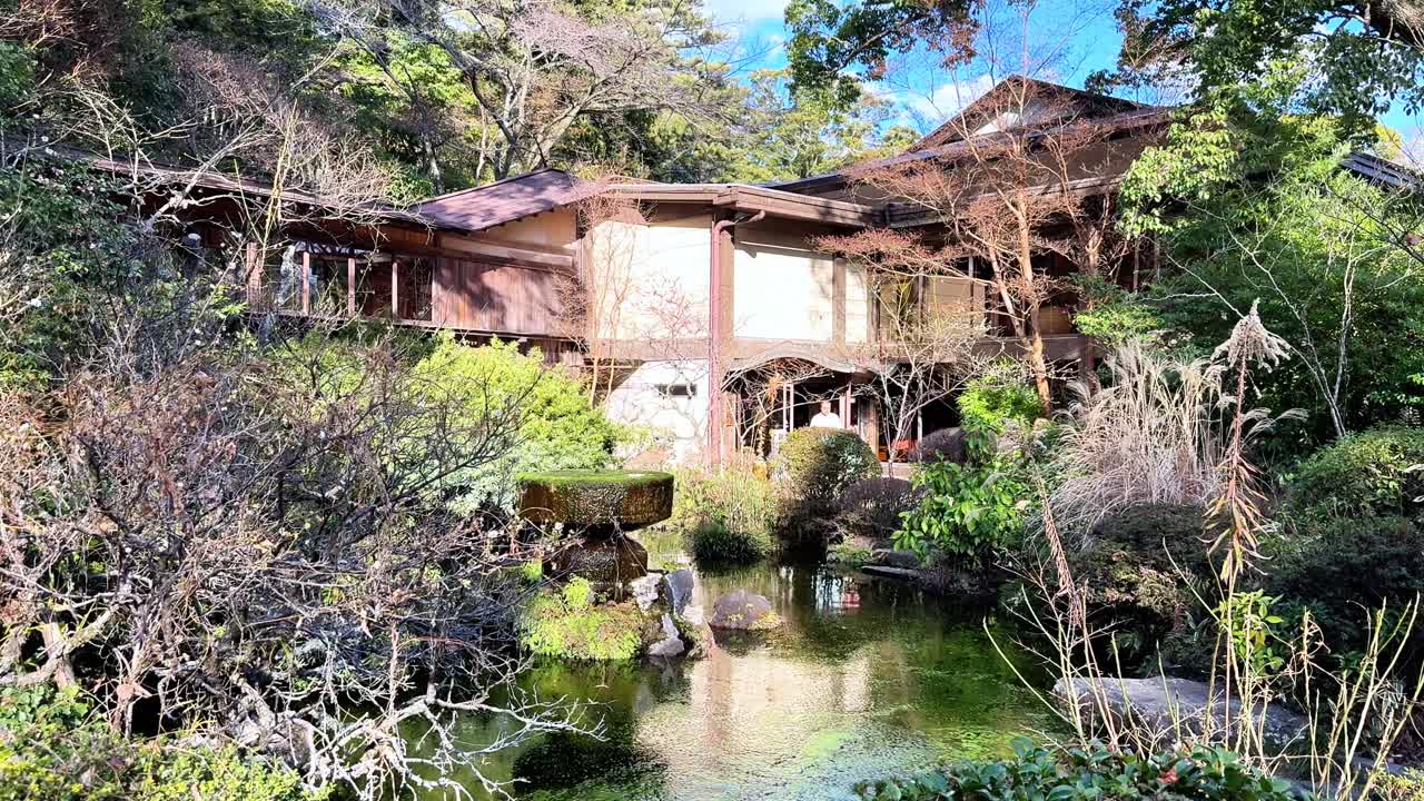 Odawara slotts trädgård med en fridfull damm och frodig grönska i solljus.