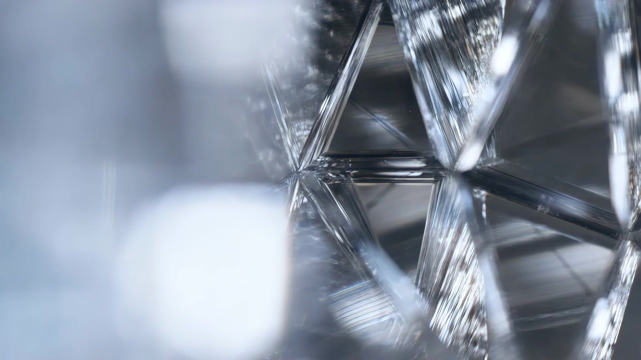 Närbild av korsande triangulära och trapetsformade glaskristallfasetter på höger sida, med skiftande reflektioner, mjuk oskarp bokeh, neutral gradient, kallt ljus, raffinerat abstrakt djup.
