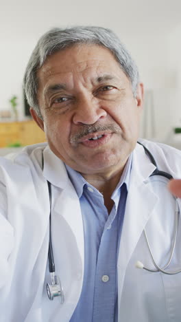 video vertical de un médico bi-racial senior amistoso hablando durante una llamada de video