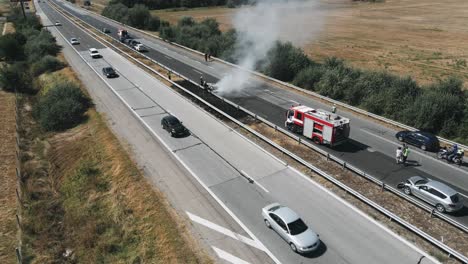 fire truck came to rescue. flow of cars on track. problem is on the road. traffic incident. firefighters extinguish burning car on highway following serious car accident on hot summer day aerial view