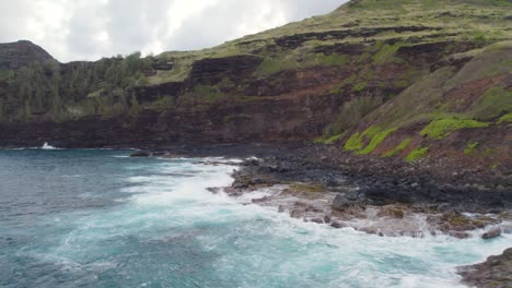 cinematic footage of azure, blue, green, turquoise waves crashing on scenic black volcanic sea cliffs and sharp rocks