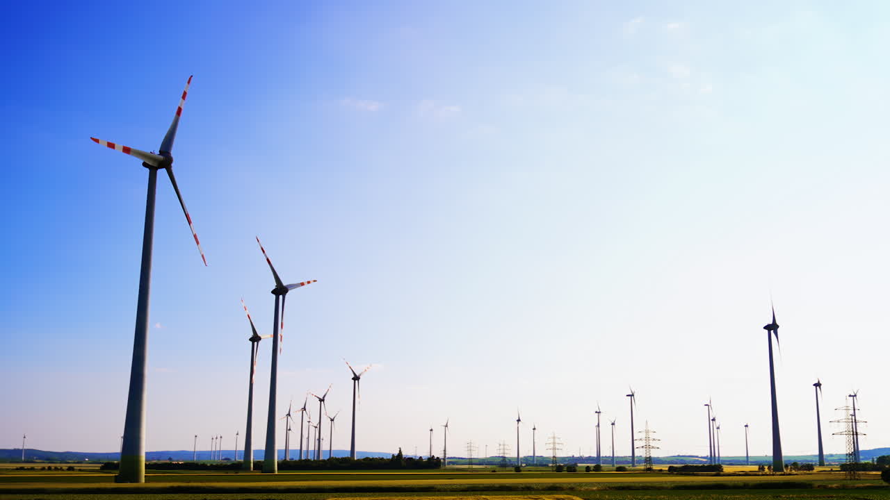 Wind turbines produce clean energy. Wind turbines stand tall in a vast landscape, harnessing wind energy against a clear sky during sunset hours