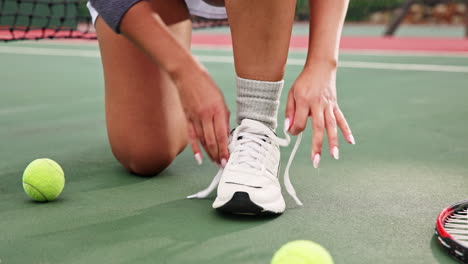 woman tying shoelaces on a tennis court