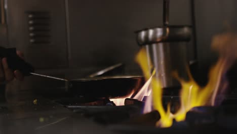 Chef-cooking-with-flaming-saucepan-over-hot-stove