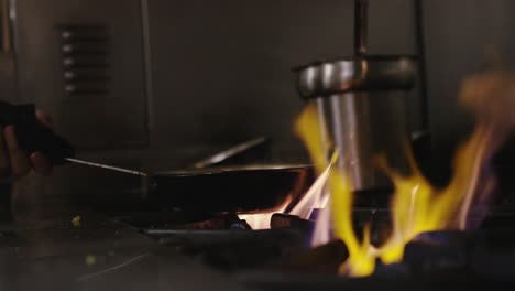 chef cocinando con una cacerola en llamas sobre una estufa caliente