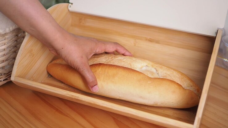 Hand Taking Fresh Baguette From Wooden Bread Box