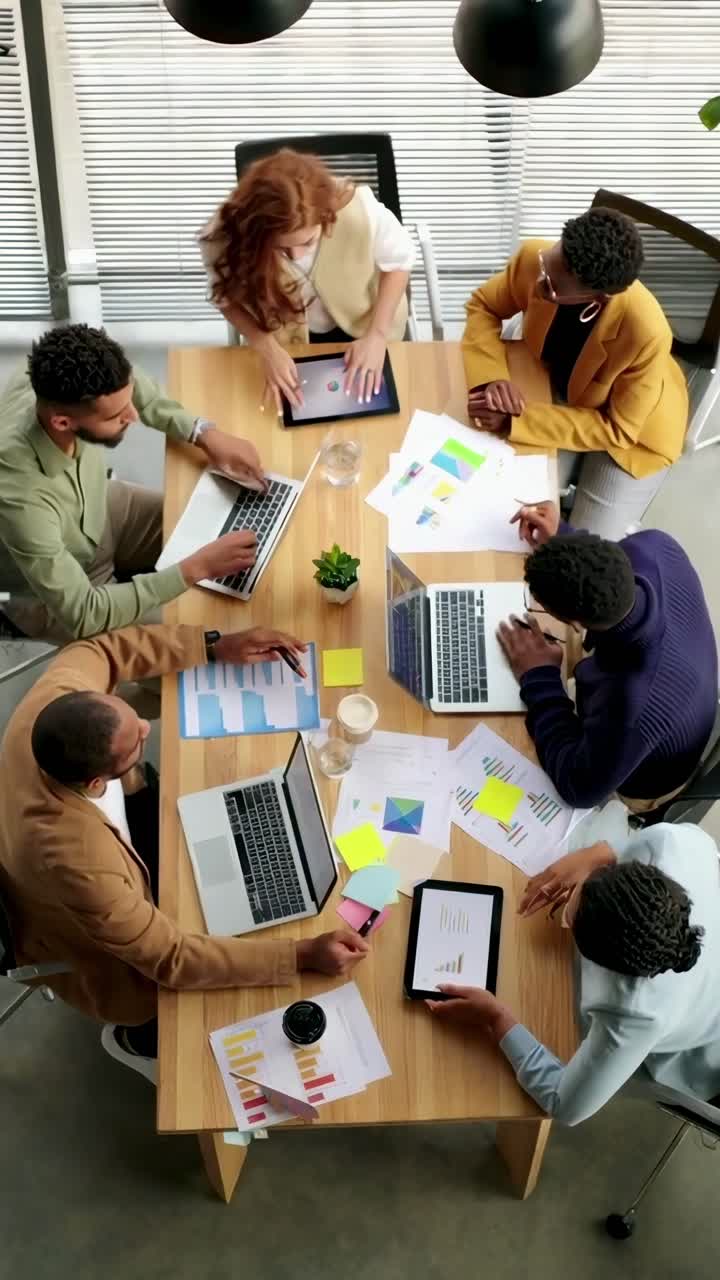 Oversigtsbillede af et mangfoldigt hold, der samarbejder ved et bord med laptops og diagrammer