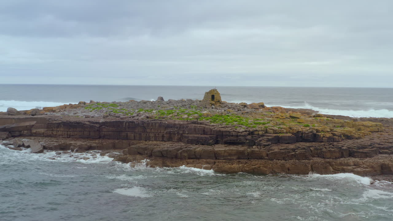 Aerial orbit of Crab Island as waves crash against the coast on a rough Atlantic day