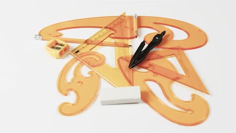 close up of compass, pencil, sharpener, eraser and rulers on white background, slow motion