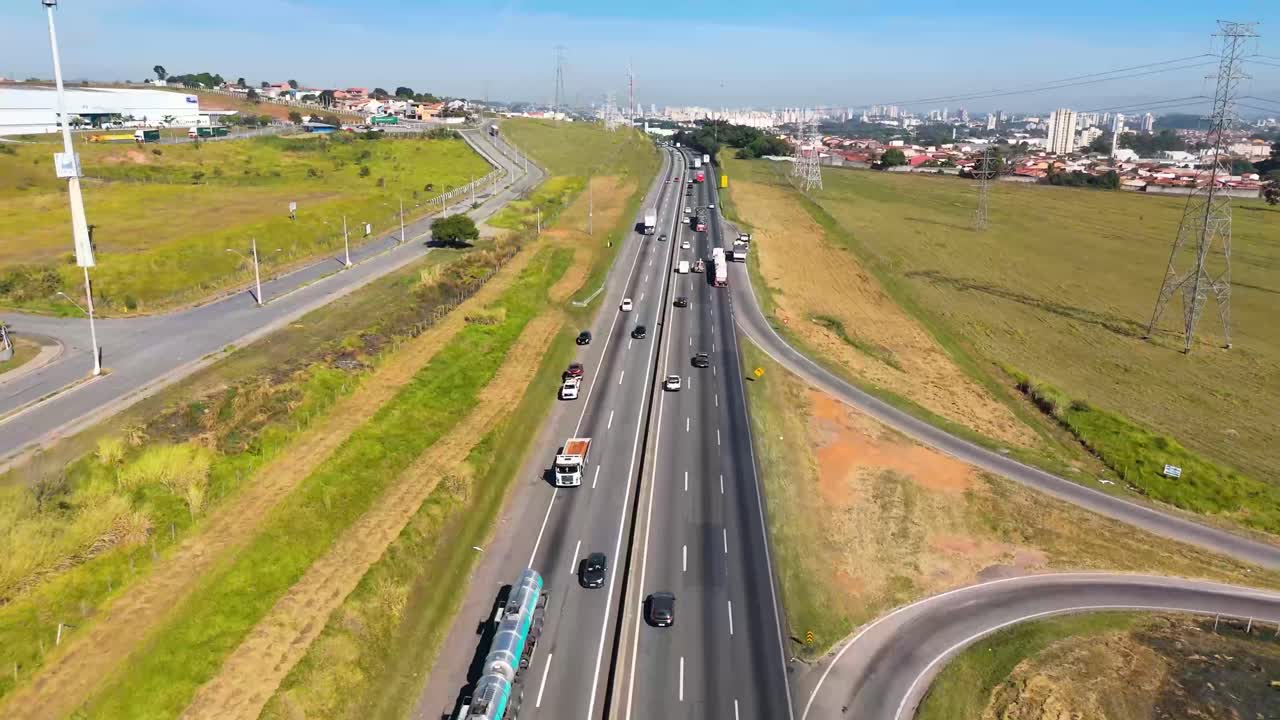 vista aérea de una autopista ocupada que pasa por una zona rural hacia un paisaje urbano lejano.