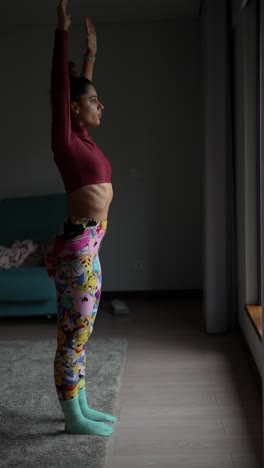 woman practicing yoga pose by window