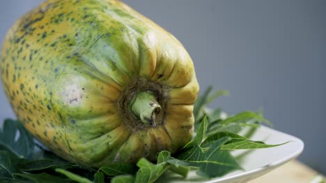 Ripe-yellow-papaya-with-spots-on-it-spinning-on-a-rotating-platform-vegan-vegetarian-fruit-paw-paw