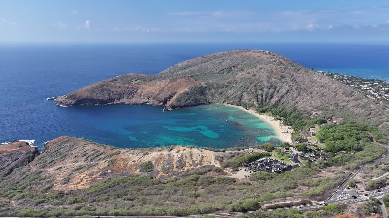 Aerial drone footage over Hanauma Bay on Oahu, Hawaii, showcasing turquoise waters, coral reefs, sandy beaches, tropical coastline, and lush vegetation along this iconic island snorkeling destination