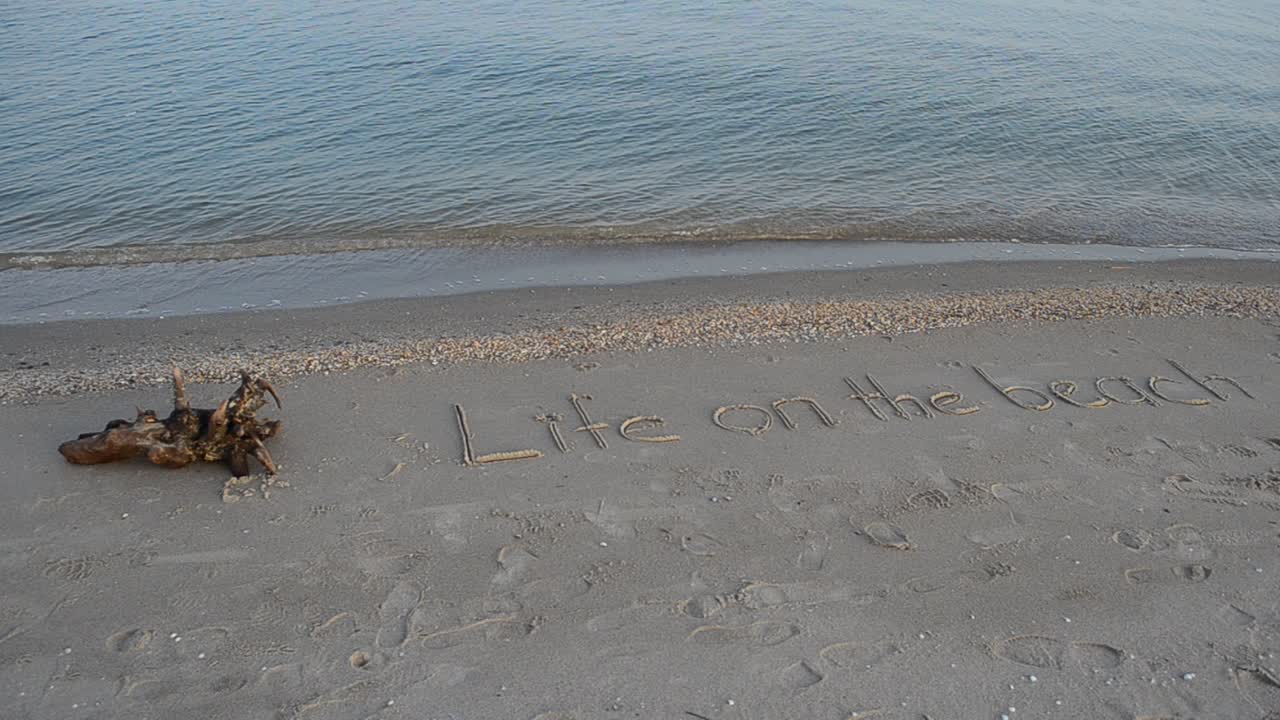 Inscription on sand, the beach. Life on the beach concept - inscription on a beach sand with coming wave