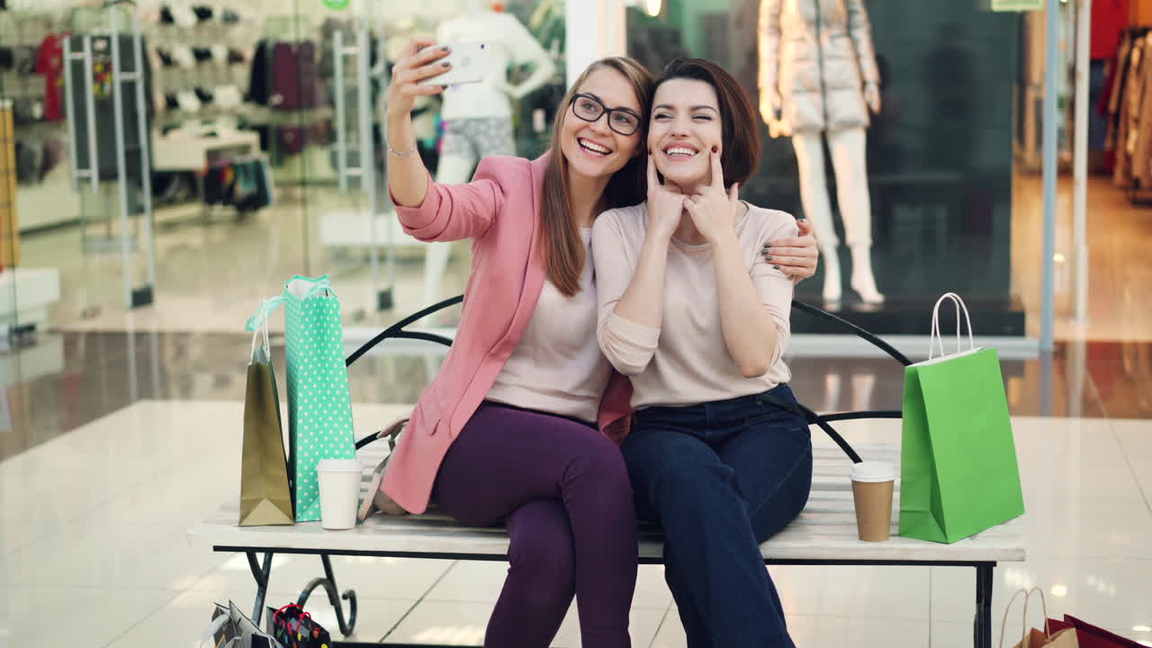Two happy friends taking a selfie in a shopping mall