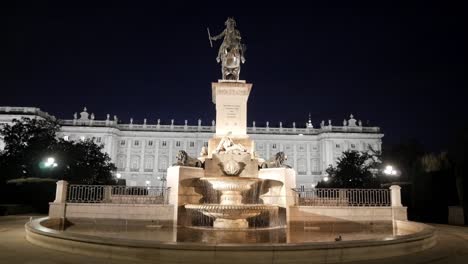 a beautifully lit fountain stands at the foot of the royal palace in madrid at night