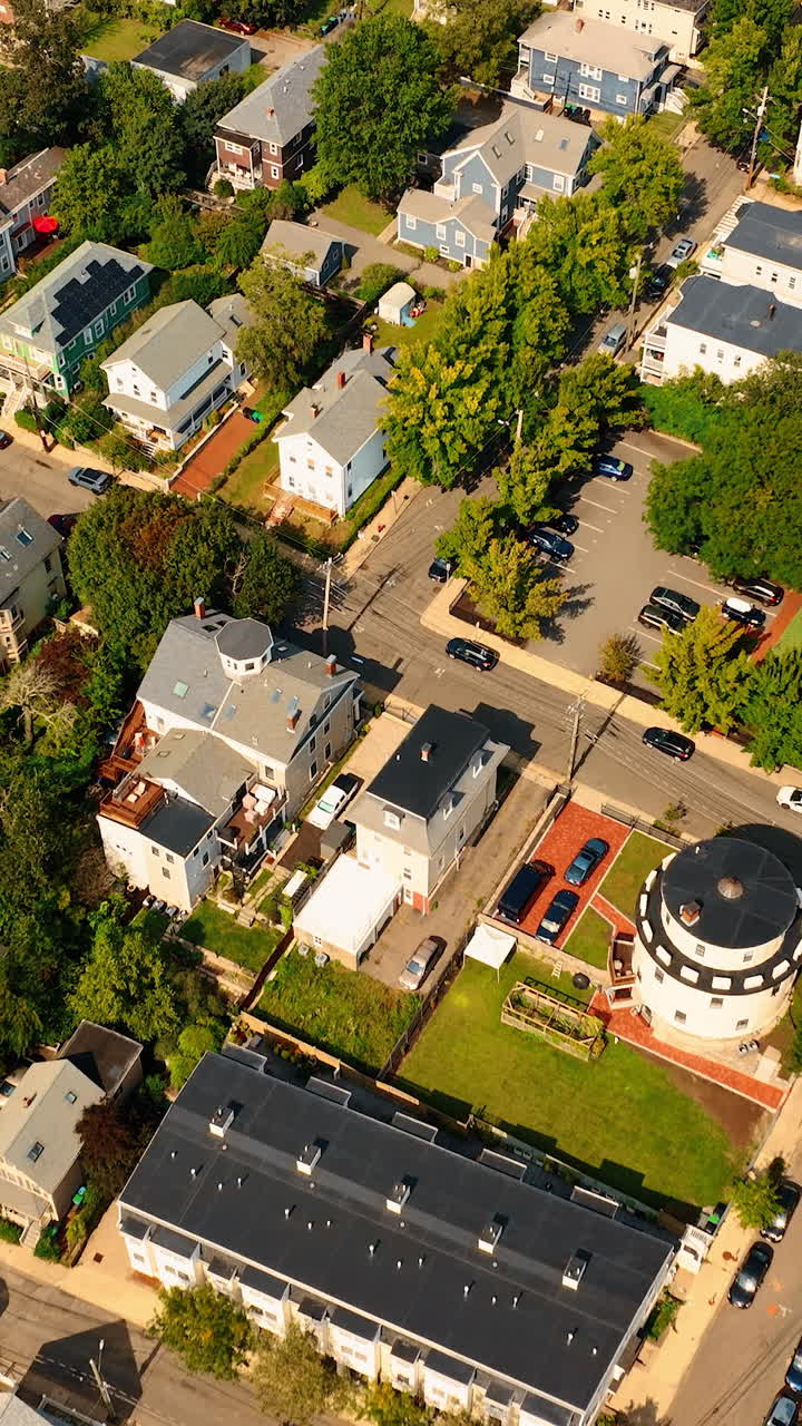 Flight above the cozy, low-rise houses in the neighborhood of Cambridge, Massachusetts, USA. Bright sunny cityscape with plenty of greenery from aerial perspective.. Vertical video