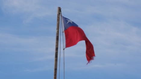 Bandera-Chilena-Ondeando-En-Un-Poste-Bajo-El-Cielo-Azul-Claro-En-Patagonia,-América-Del-Sur