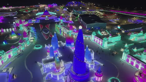 aerial rotates over frozen ice festival grounds at night, colourful