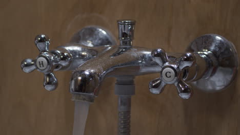 Hand-turns-hot-water-handle-to-turn-on-bath-water-faucet