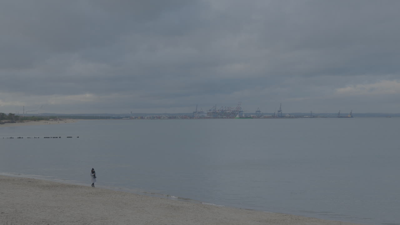 흐린 날 동안 모래 해변에서 바다와 도시 그단스크를 바라보는 사람의 공중 전망