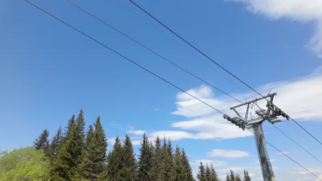 Empty-Chairlift-Seat-passing-above,-on-a-sunny-summer-day