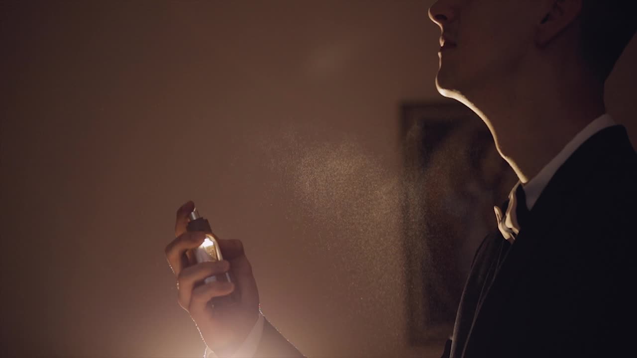 Lo sposo si spruzza il profumo. Giorno del matrimonio. Movimento lento