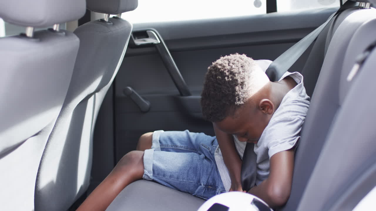 아프리카계 미국인 소년이 차에서 안전벨트를 습니다.