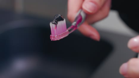 person putting toothpaste on toothbrush - oral hygiene concept