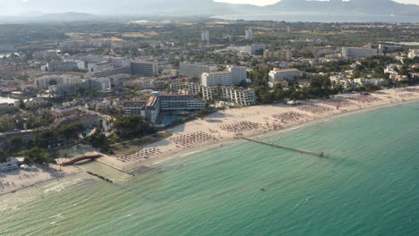 Sandy-beach-in-Alcudia-city-with-touristic-hotel-resorts-and-sea-jetty