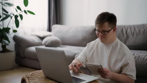 Down-syndrome-young-adult-man-sitting-at-home,-using-laptop-for-learning