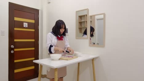 medium shot of a young woman chef wincing in pain and crying from cutting onions on a chopping board