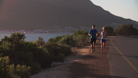 Couple-running-towards-camera-on-empty-road,-slow-motion