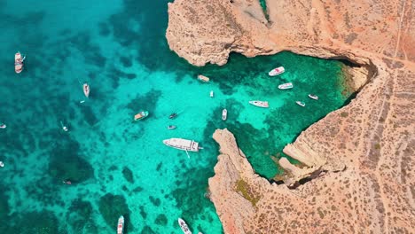 impresionante video aéreo de crystal lagoon, malta, capturando la serena belleza de los barcos anclados en las vibrantes aguas turquesas rodeados de escarpados acantilados costeros